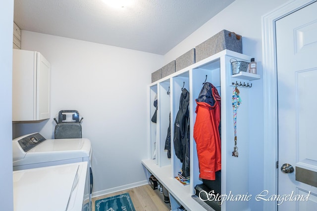 5337 Division Ave N, Comstock Park, MI 49321 - laundry area featuring washer and dryer, light wood-type flooring, cabinet space, a textured ceiling, and baseboards