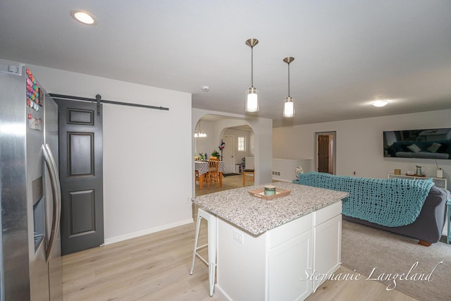 5337 Division Ave N, Comstock Park, MI 49321 - kitchen featuring stainless steel fridge, arched walkways, white cabinets, open floor plan, and light wood-style flooring