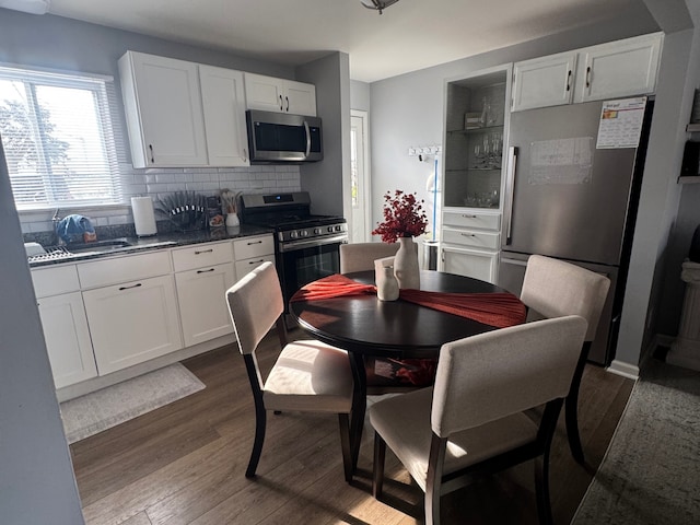 kitchen featuring appliances with stainless steel finishes, dark hardwood / wood-style floors, white cabinetry, sink, and backsplash