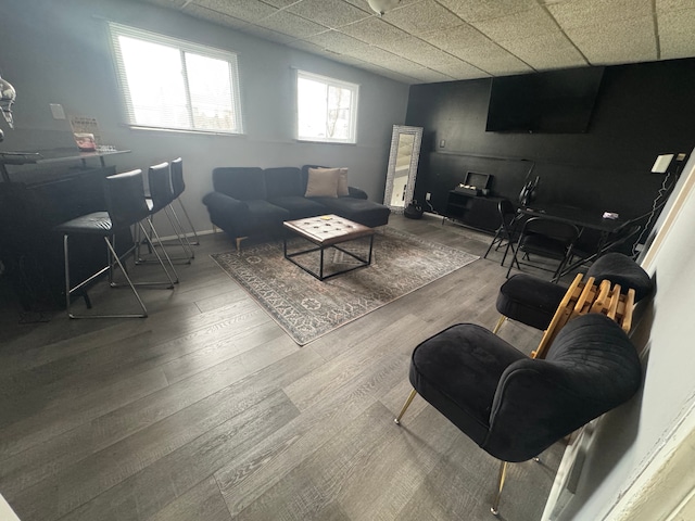 living room featuring wood-type flooring and a drop ceiling