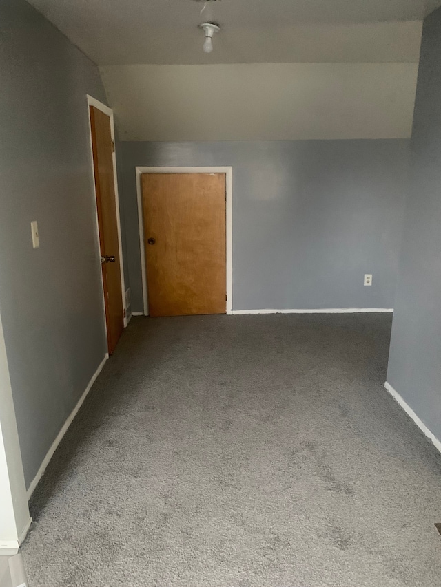 spare room with carpet floors and vaulted ceiling