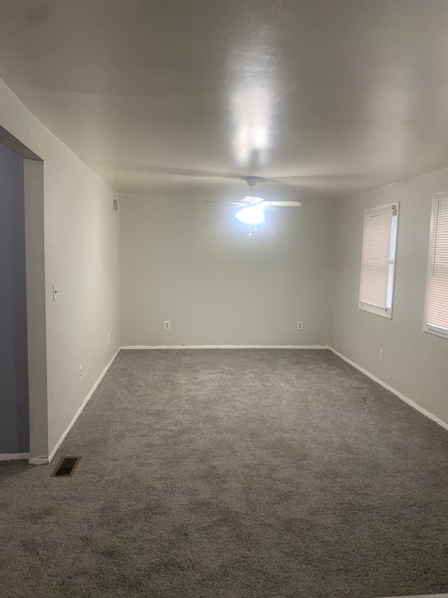 spare room featuring dark colored carpet and ceiling fan