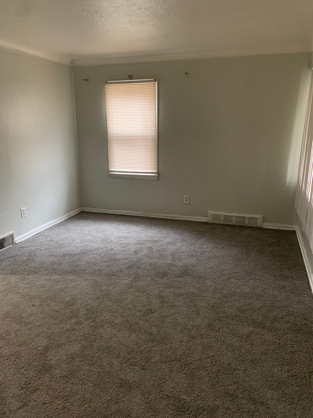 empty room with dark colored carpet and a textured ceiling