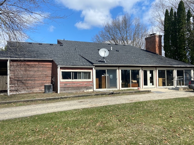 8899 Dwyer Rd, Howell, MI 48855 - rear view of house with a shingled roof, a chimney, a yard, and central AC