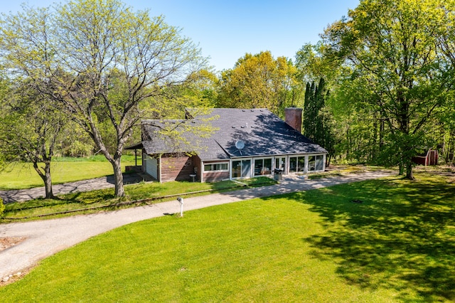 8899 Dwyer Rd, Howell, MI 48855 - view of front of house with a front lawn, a chimney, driveway, and covered porch