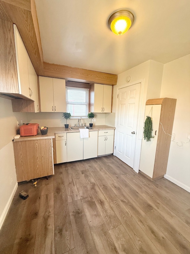 kitchen with white cabinetry, light hardwood / wood-style flooring, and sink