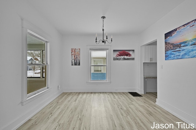 unfurnished dining area featuring a chandelier and light wood-type flooring