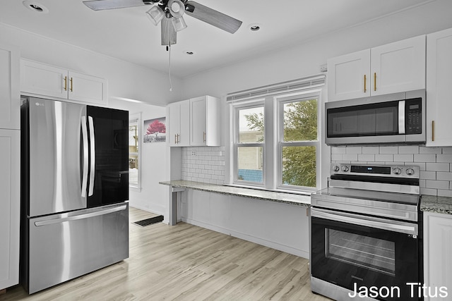 kitchen featuring decorative backsplash, appliances with stainless steel finishes, light wood-type flooring, light stone countertops, and white cabinetry