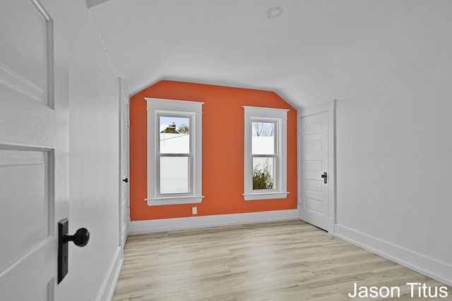 additional living space with light wood-type flooring and vaulted ceiling