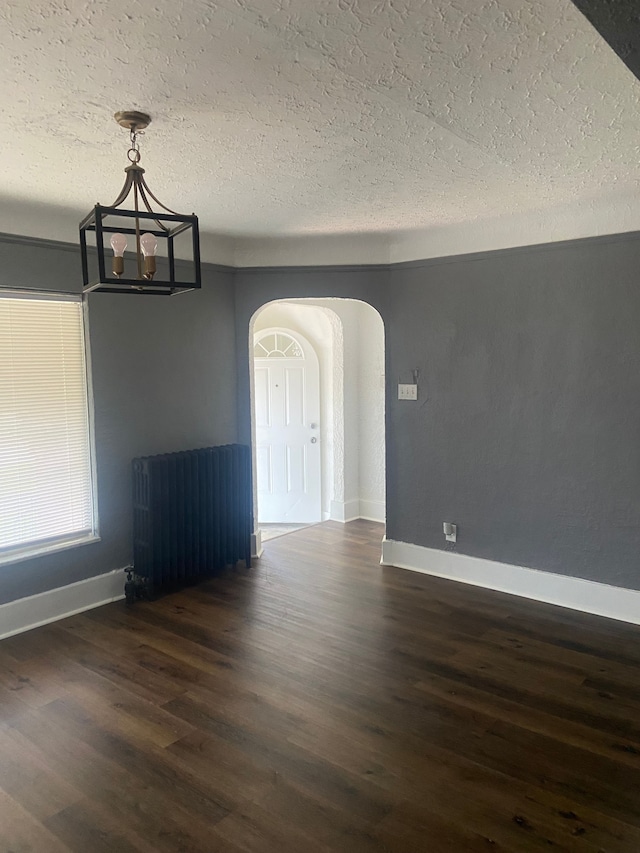 unfurnished dining area featuring a textured ceiling and dark wood-type flooring