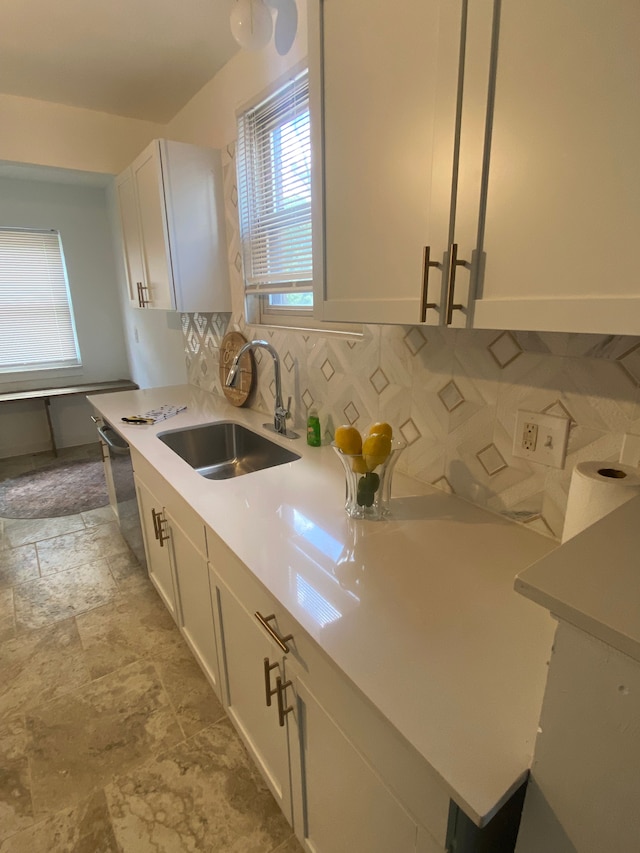 kitchen with dishwasher, white cabinetry, sink, and tasteful backsplash