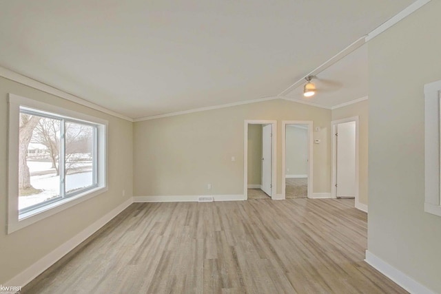 empty room with lofted ceiling, ceiling fan, ornamental molding, and light hardwood / wood-style flooring