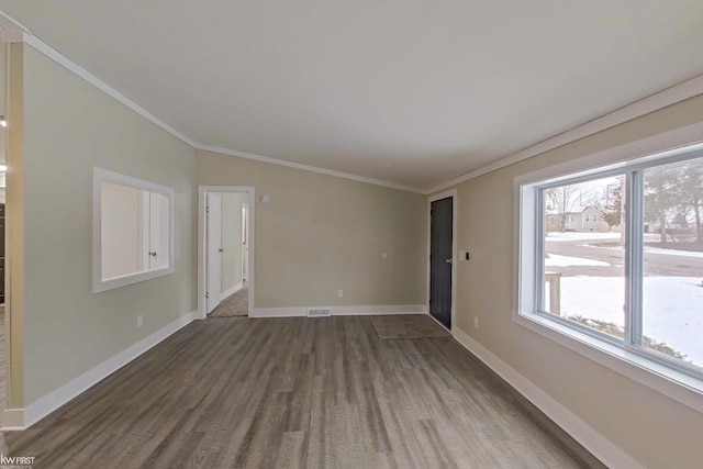 empty room featuring a wealth of natural light, crown molding, and dark hardwood / wood-style floors