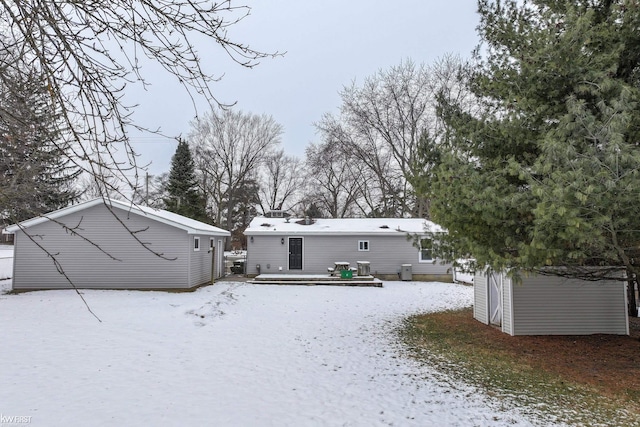 snow covered back of property with a deck