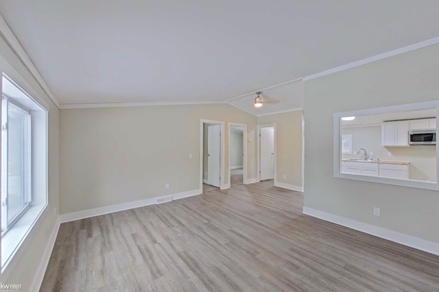 unfurnished room with light hardwood / wood-style floors, ornamental molding, sink, and vaulted ceiling