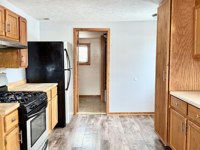 kitchen featuring light wood-type flooring, a textured ceiling, and gas range