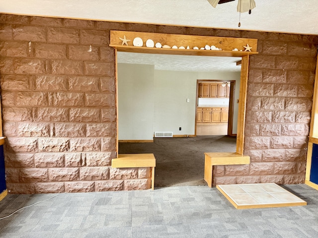 interior space featuring ceiling fan, carpet floors, and a textured ceiling