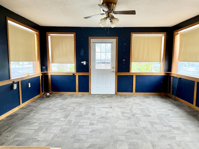 carpeted spare room featuring ceiling fan, a textured ceiling, and a wealth of natural light