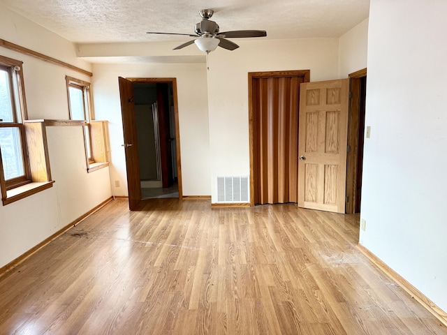 empty room with ceiling fan, light hardwood / wood-style flooring, and a textured ceiling