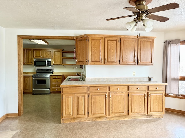 kitchen with ceiling fan, sink, a textured ceiling, and appliances with stainless steel finishes