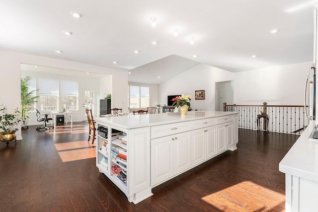 kitchen with white cabinets, dark hardwood / wood-style floors, a kitchen island, and lofted ceiling