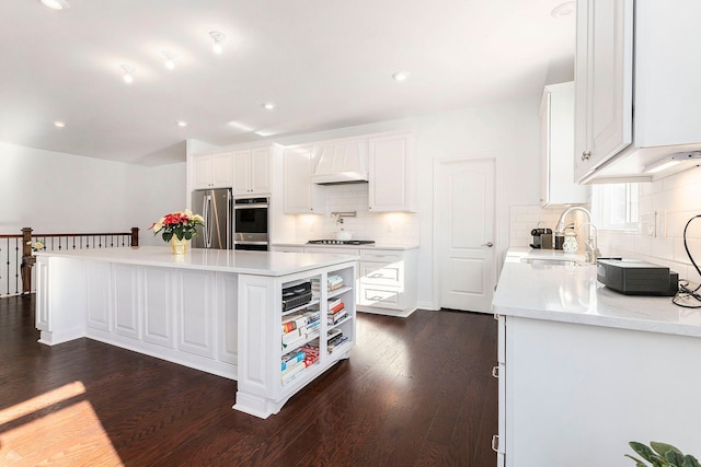 kitchen with dark wood-type flooring, white cabinets, sink, a kitchen island, and stainless steel appliances