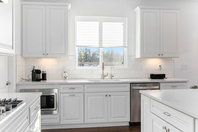 kitchen featuring white cabinets, backsplash, sink, and appliances with stainless steel finishes