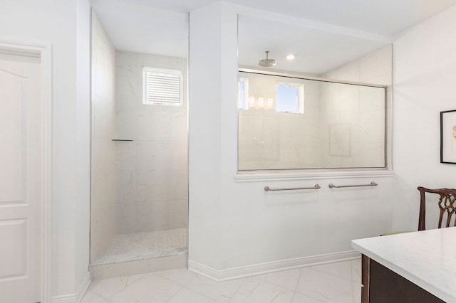 bathroom with vanity, a tile shower, and a wealth of natural light