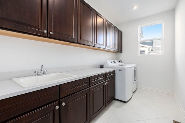 washroom with washer and clothes dryer, sink, light tile patterned floors, and cabinets