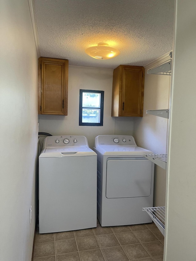 washroom featuring cabinets, a textured ceiling, and washing machine and dryer