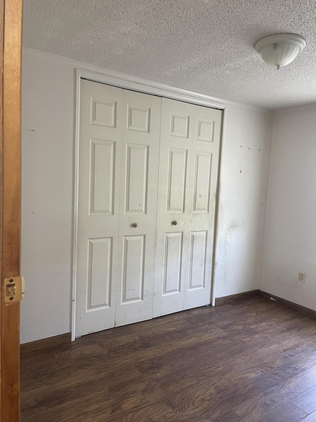 unfurnished bedroom featuring a textured ceiling, dark wood-type flooring, and a closet