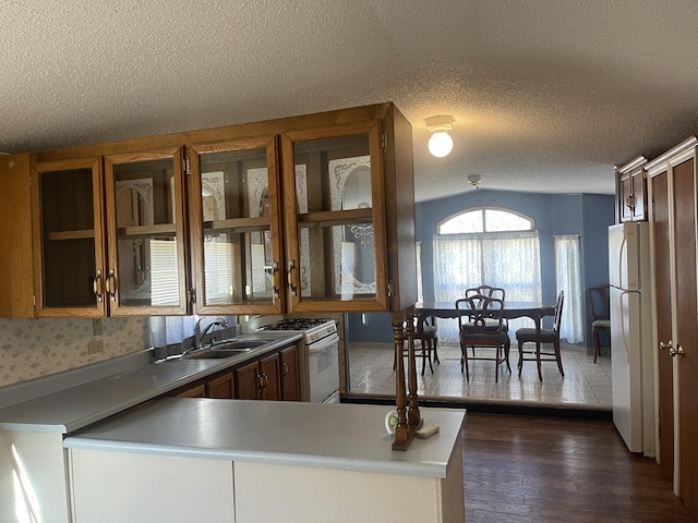 kitchen with white appliances, sink, a textured ceiling, dark hardwood / wood-style flooring, and kitchen peninsula