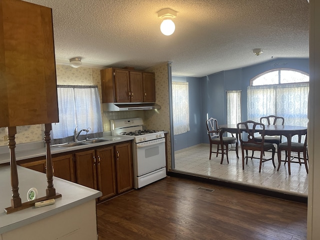 kitchen featuring sink, dark wood-type flooring, a textured ceiling, lofted ceiling, and white gas range oven