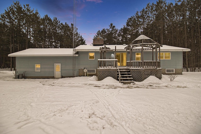 snow covered rear of property with a gazebo and a wooden deck