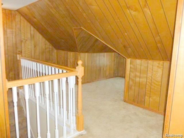 additional living space with wooden walls, wood ceiling, vaulted ceiling, and light carpet