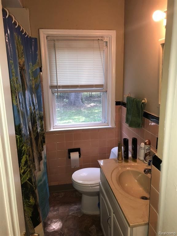 bathroom with vanity, toilet, and tile walls