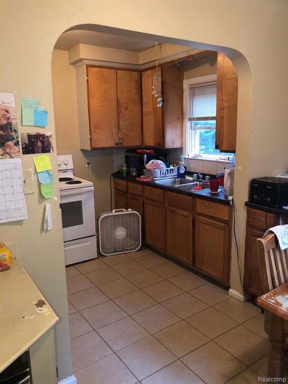 kitchen featuring white range with electric cooktop, sink, and light tile patterned floors