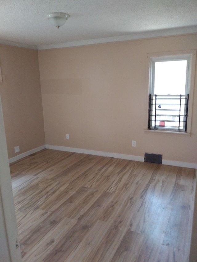 spare room featuring a textured ceiling and light hardwood / wood-style flooring