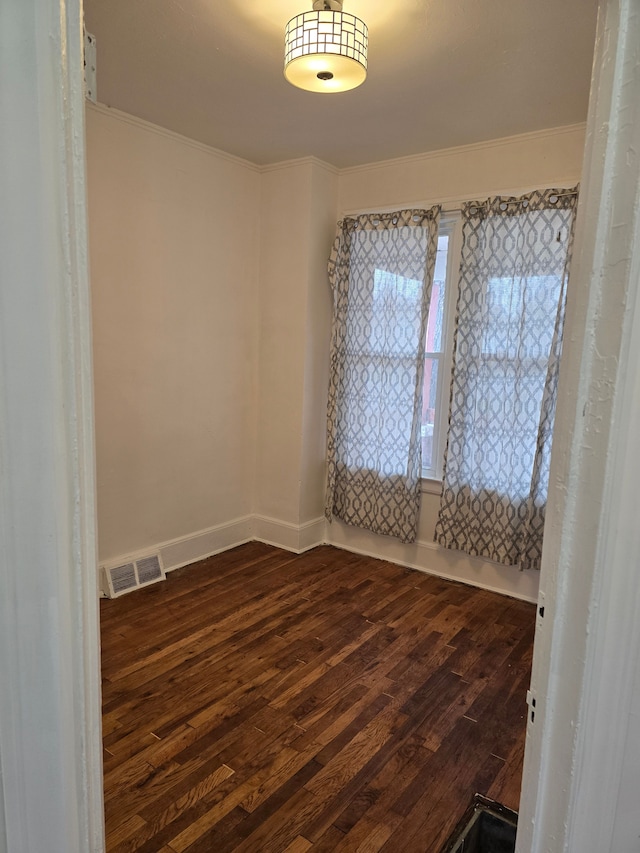 spare room with dark hardwood / wood-style flooring and crown molding