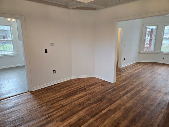 spare room with a chandelier, beam ceiling, dark wood-type flooring, and coffered ceiling