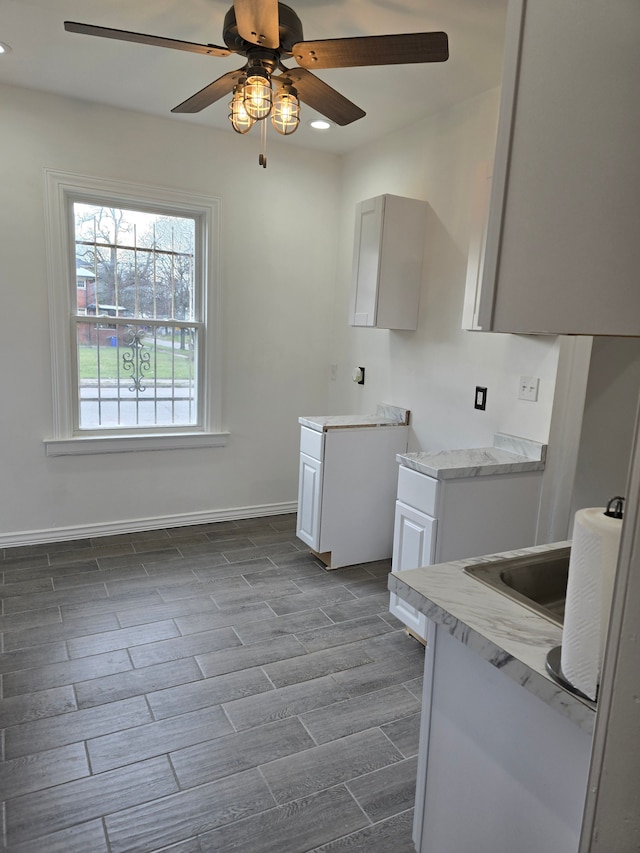 kitchen with ceiling fan and white cabinetry