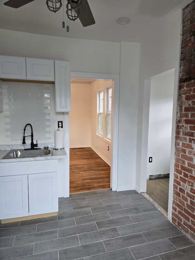 kitchen with decorative backsplash, white cabinetry, ceiling fan, and sink