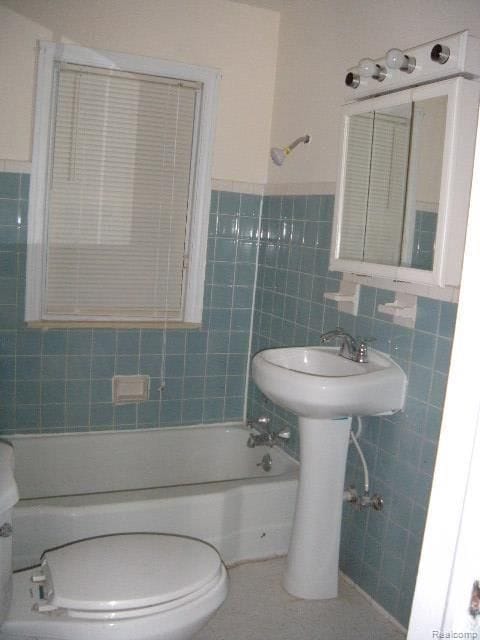 bathroom featuring bathing tub / shower combination, tile walls, and toilet