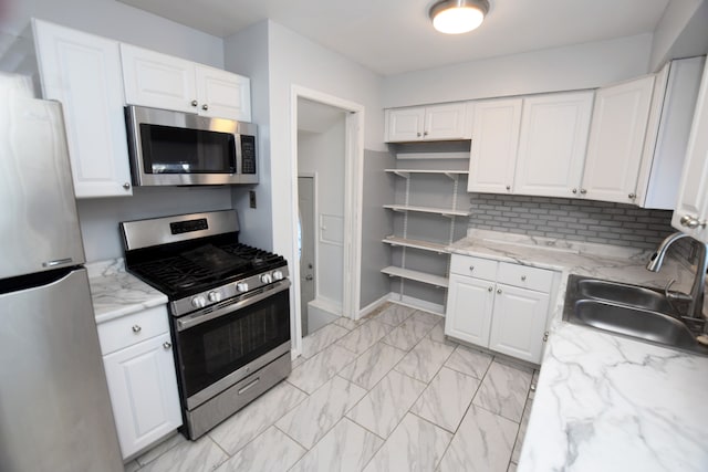 kitchen featuring appliances with stainless steel finishes, white cabinets, tasteful backsplash, and sink