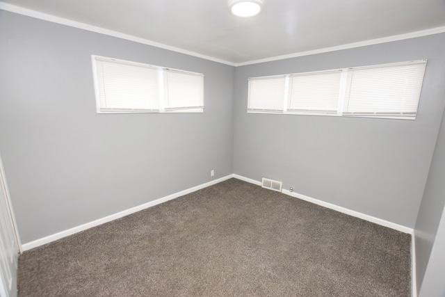 spare room with ornamental molding and dark colored carpet