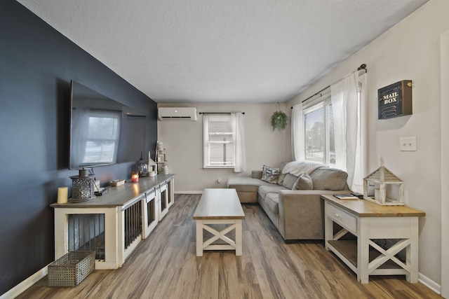 living room featuring hardwood / wood-style flooring, a wall mounted AC, and a textured ceiling