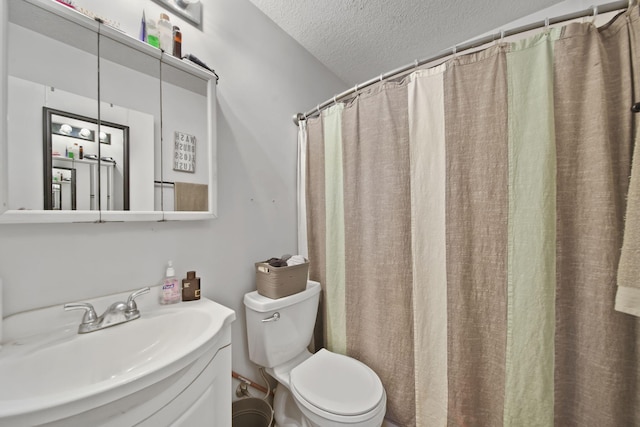 bathroom featuring toilet, vanity, a textured ceiling, and walk in shower