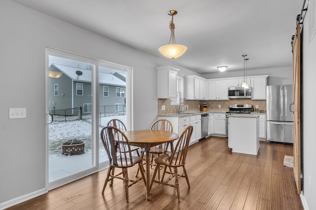 dining space with a barn door, light hardwood / wood-style floors, plenty of natural light, and sink