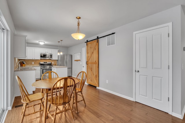 dining area featuring a barn door, light hardwood / wood-style floors, and sink