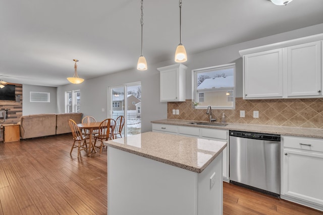 kitchen featuring backsplash, stainless steel dishwasher, sink, pendant lighting, and white cabinets